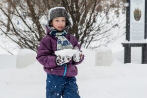 雪の中立つコートを着た子供
