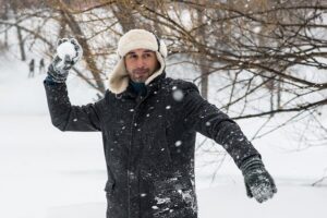 雪玉を投げようとしているコートを着た男性