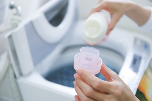 洗濯機の前で洗剤を入れるシーン
