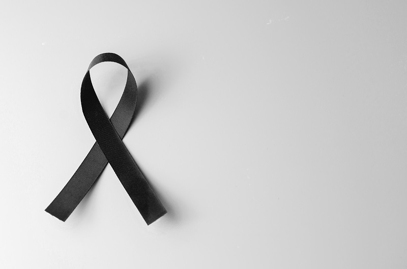 Black awareness ribbon on gray background.